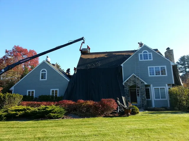 Crane lifting roofing materials onto a two-story home