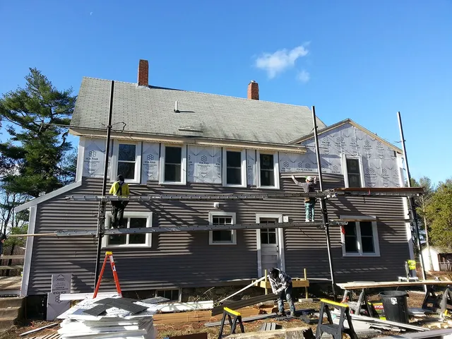 Older two-story home being resided with scaffolding in place