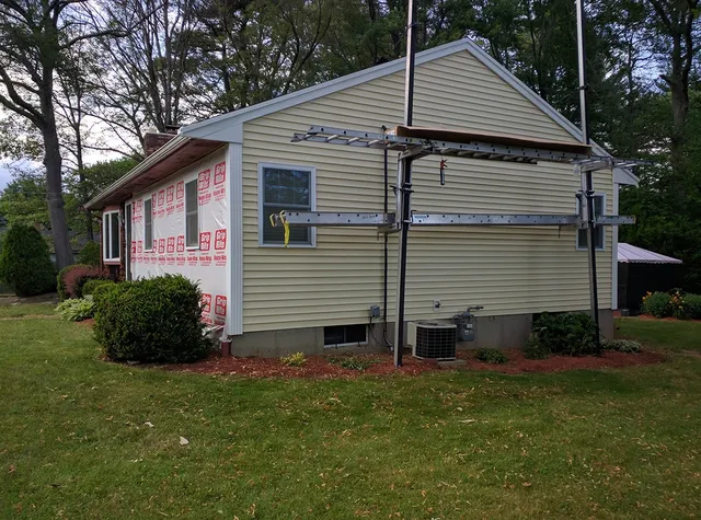 Yellow ranch home with scaffolding during a siding project