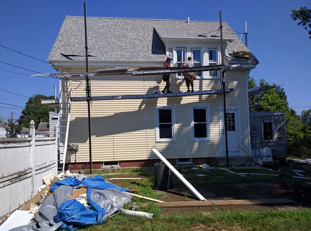 Crew working from scaffolding on a light yellow home
