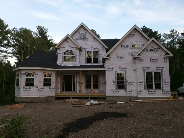 Home with a new dark roof and white house wrap on the walls