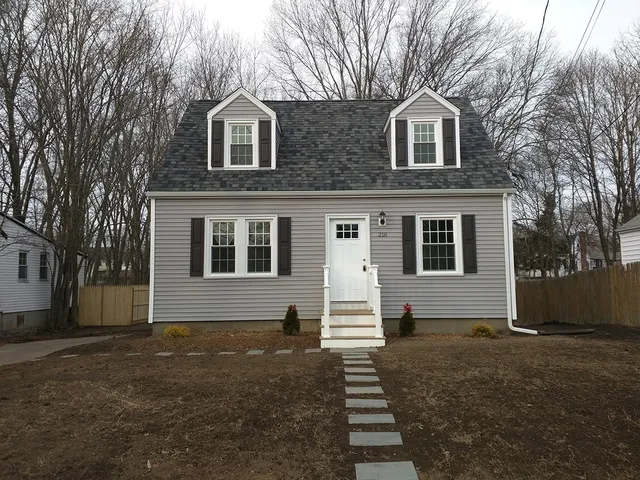 Gray cape home with new siding, dormers and black shutters