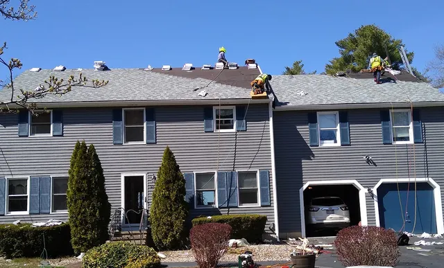 Gray colonial with crew working on the roof