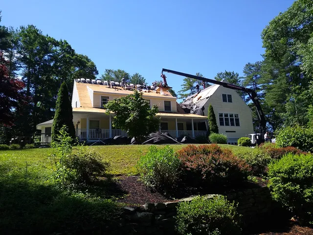 Crane lifting materials to the roof of a large yellow home