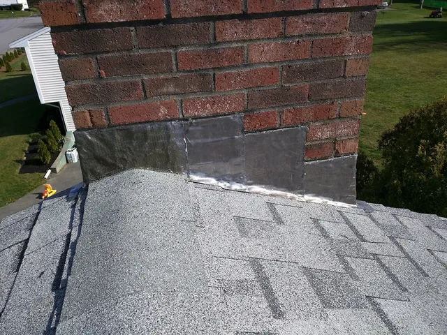 New shingles and lead flashing at a brick chimney