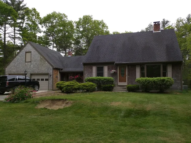 Ranch home with a dark roof and brown shingle siding