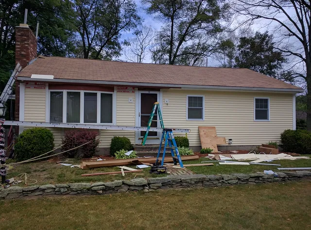 Yellow ranch home with siding work in progress