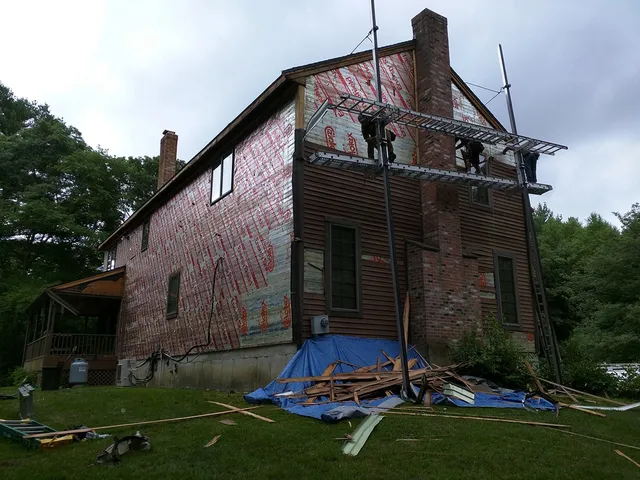 Large home stripped of old siding with scaffolding up
