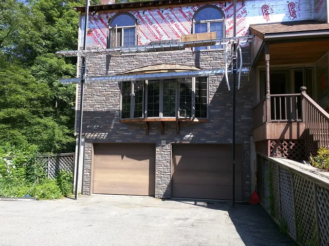 Stone veneer garage wall with new siding above