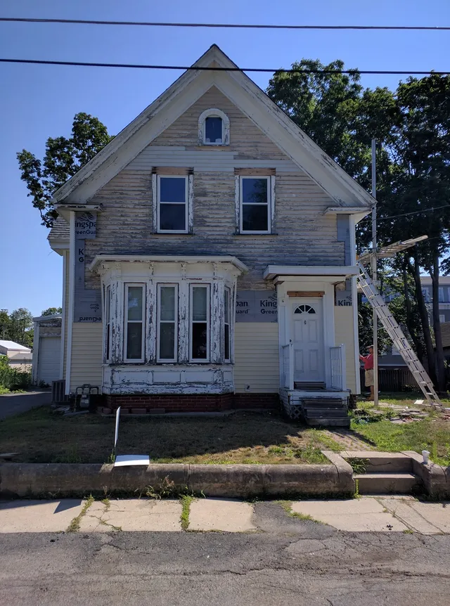 Older home with a stone foundation before new siding